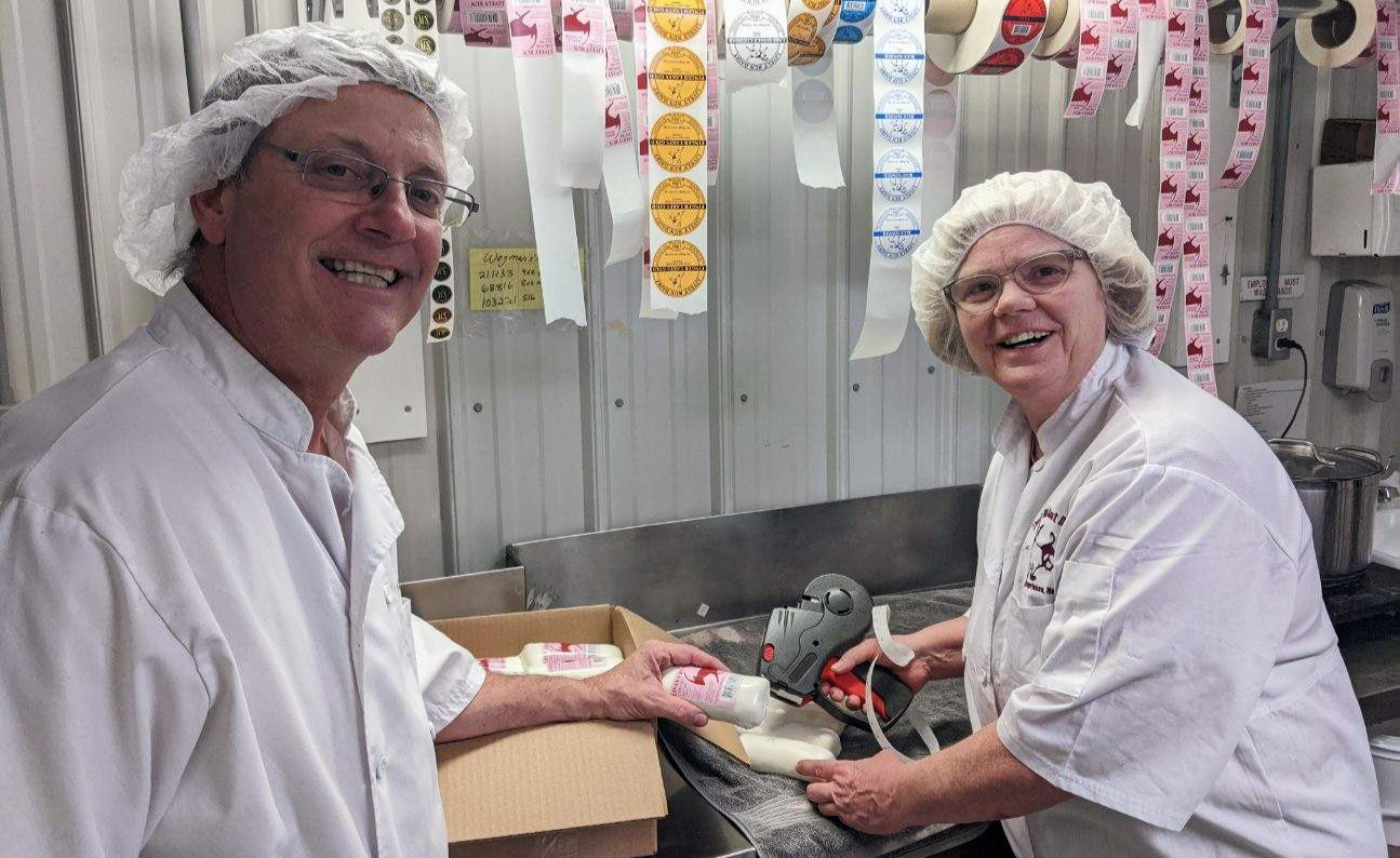 Two people in a food processing plant with packaging equipment in the background.
